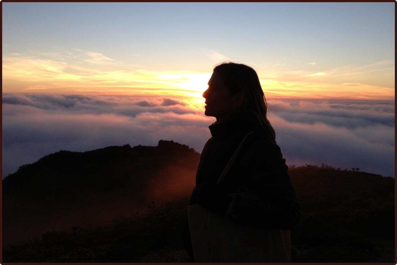 Serene image of a woman standing gracefully atop a hill.